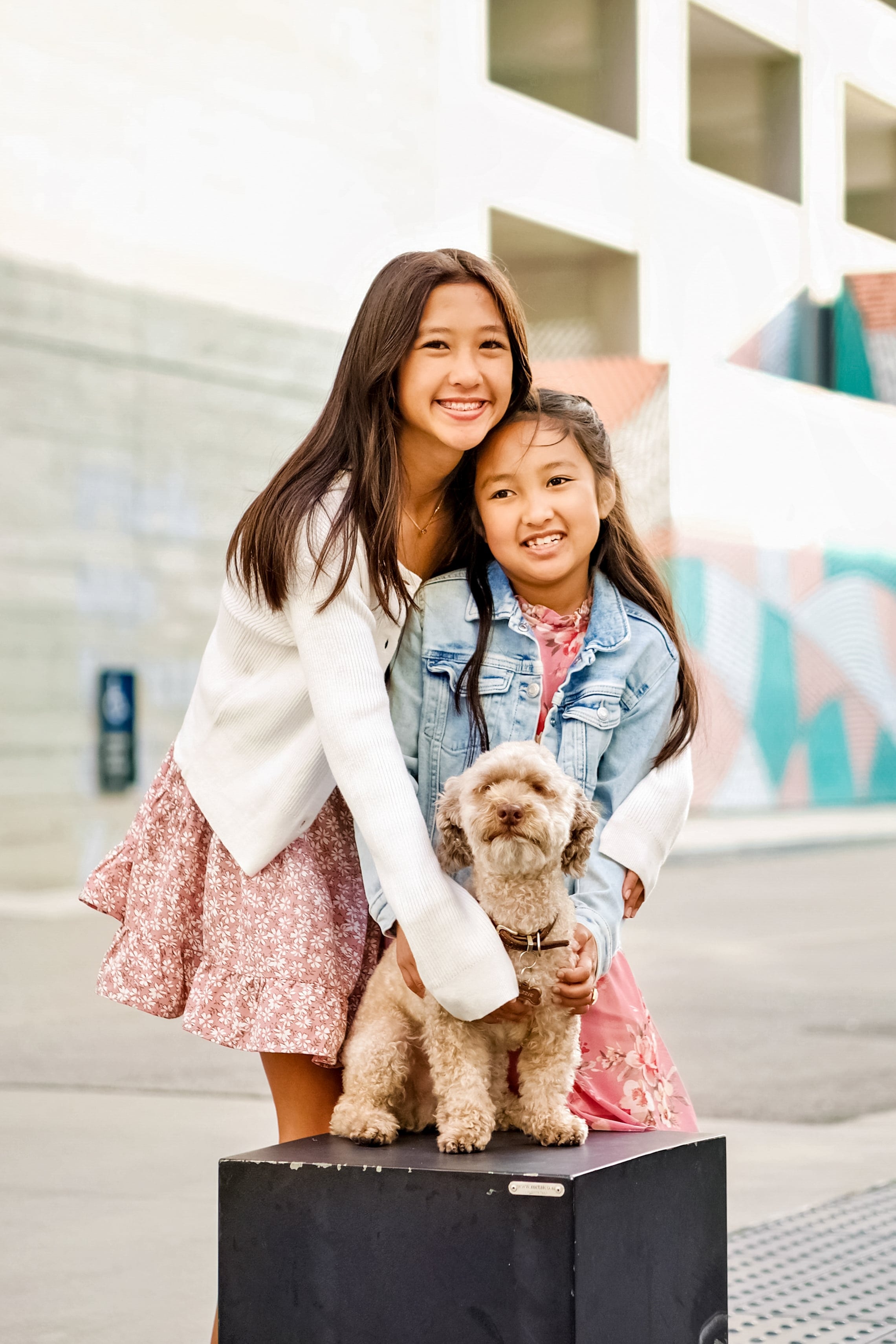 Sisters laughing together with their dog during a Sparq photo session