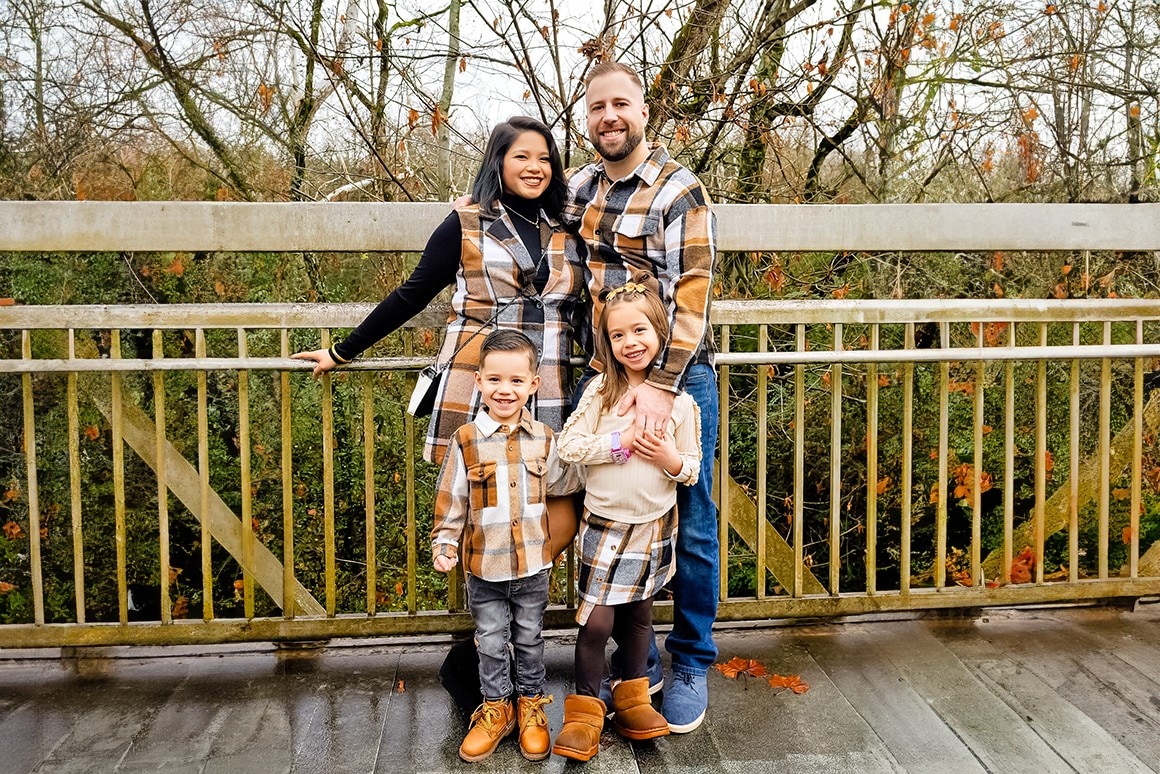Family of four in matching plaid on a bridge during an autumn photo session